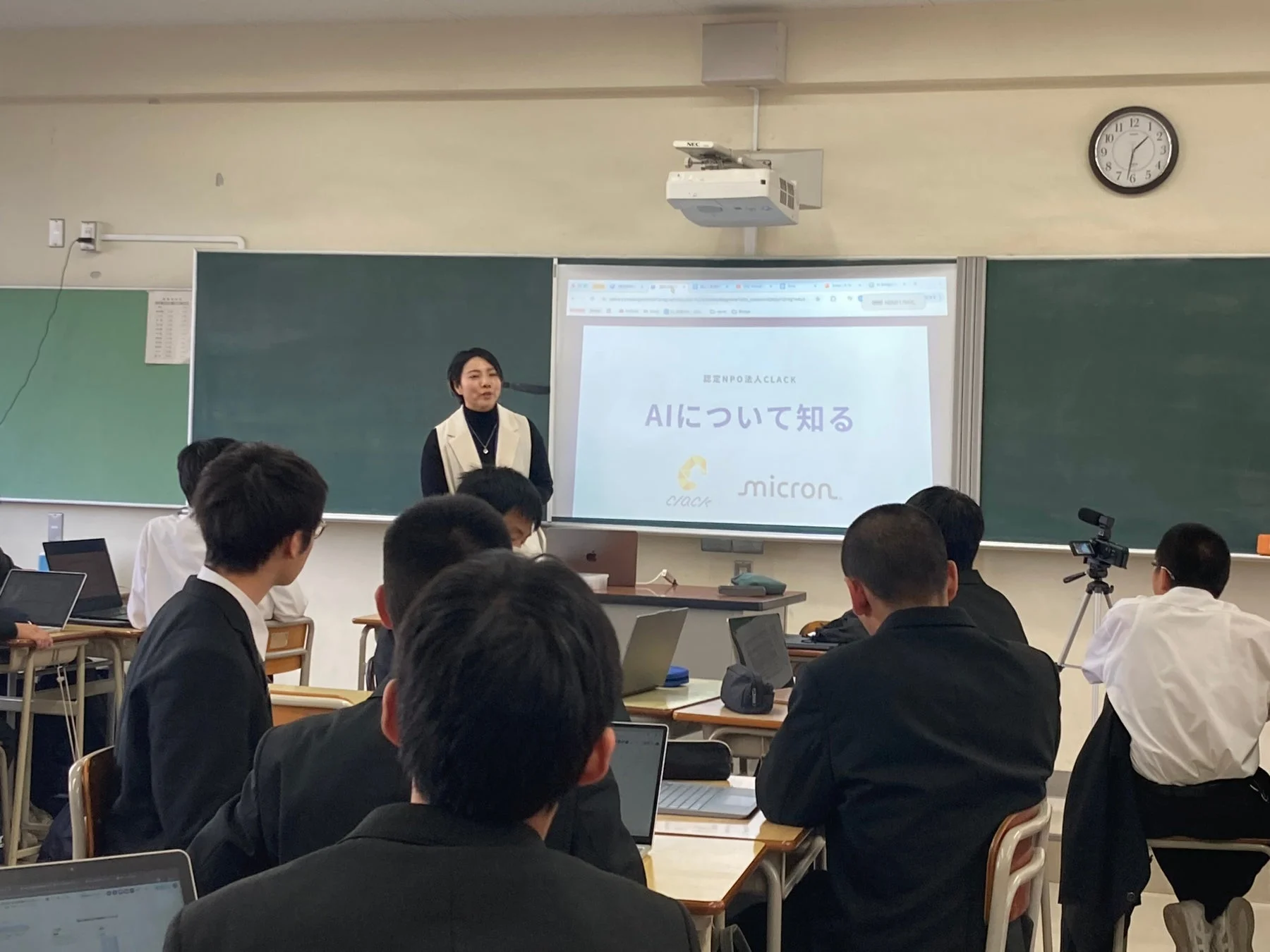 教室でAIに関するプレゼンテーションを聞く学生たち