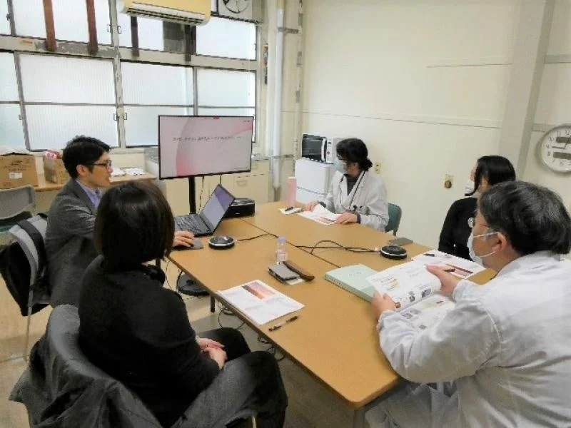 会議室でプレゼンテーションを聞く参加者たち