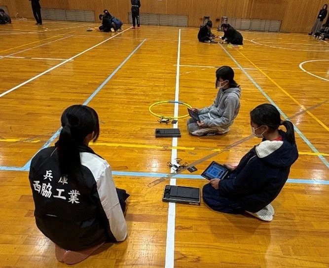 体育館でドローンを操作する生徒たち