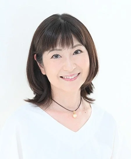 白い背景の前で、ショートヘアの日本人女性が優しい笑顔を見せているポートレート写真