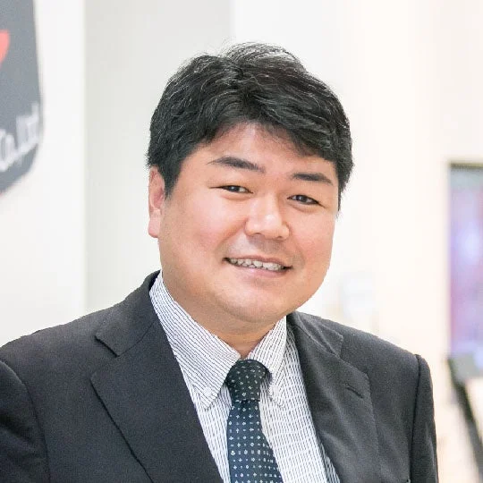 スーツを着用したアジア人男性が笑顔でカメラを見ているポートレート写真