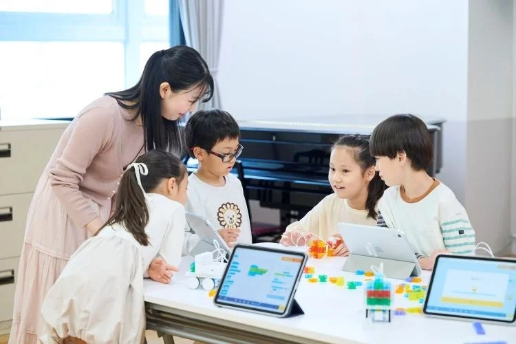 グループでプログラミング学習に取り組む子どもたちと先生