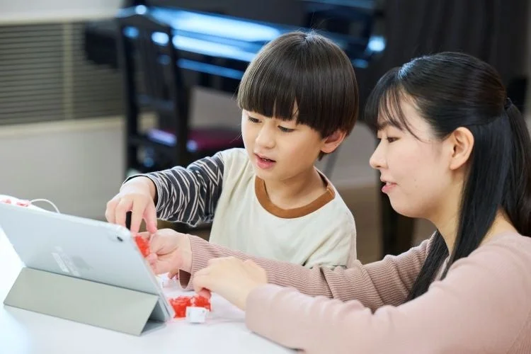 タブレットでプログラミング学習をする子どもと保護者